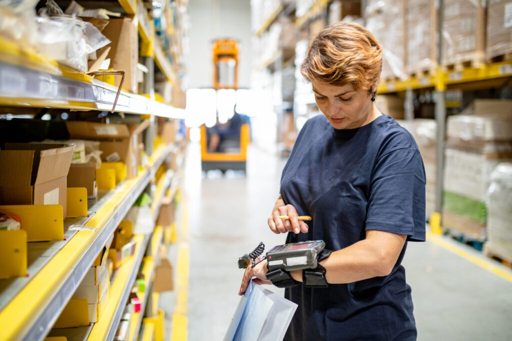 Female warehouse employee using multiple wearable technologies on her hand and wrist to prevent repetitive motion injury.