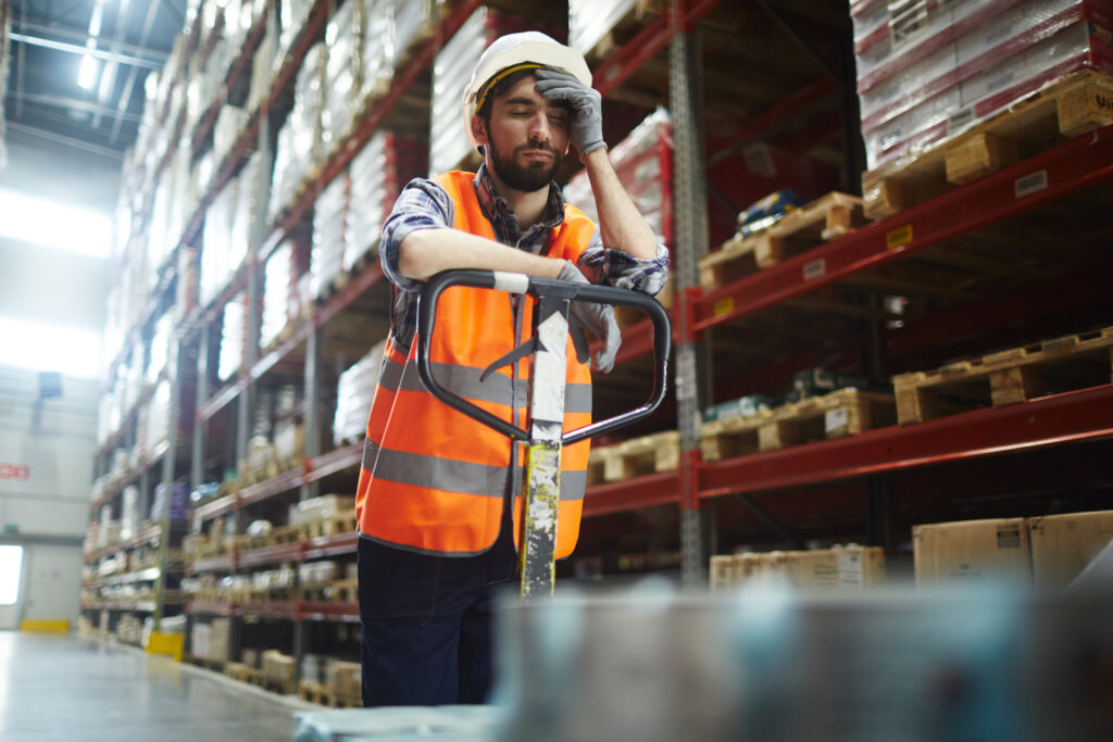 Tired worker with forklift touching his forehead