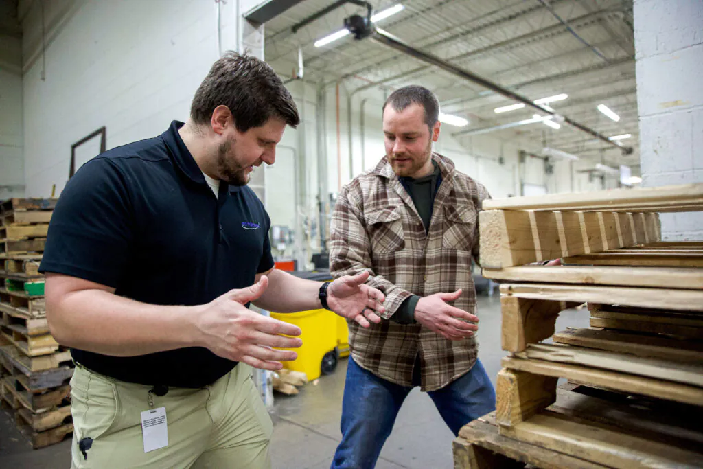 provider helping worker lift correctly in warehouse