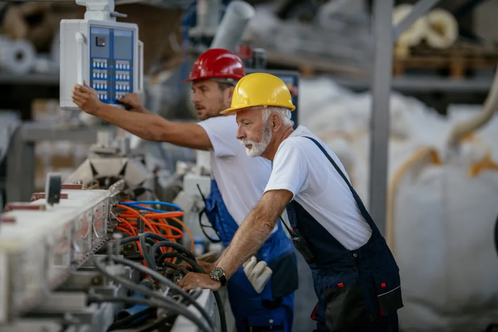 An older worker and a younger worker in PVC factory.