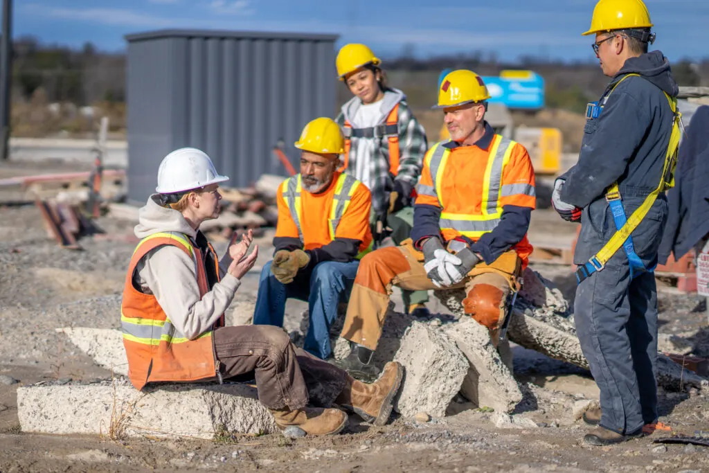 A small group of construction workers gather around as they collaborate their ideas to successfully execute the days tasks together.