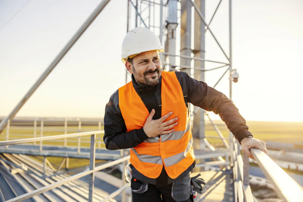 A heavy industry worker feeling chest pain on silo.