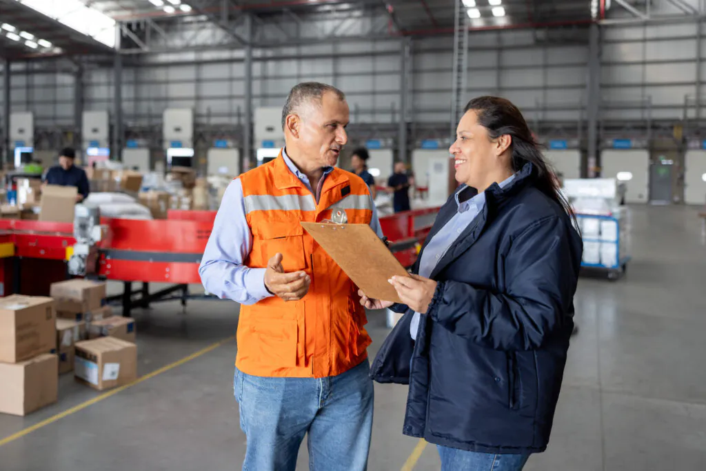 Inspector talking to a warehouse employee while holding a clipboard